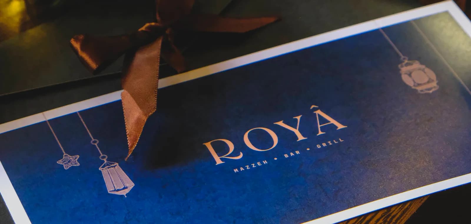 A Royâ gift voucher tied with ribbon beside the Christmas tree